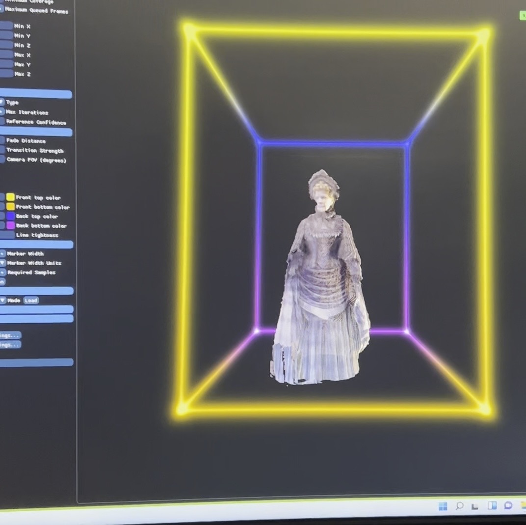 The actress in her period costume, reconstructed as a volumetric point cloud inside the wireframe capture volume