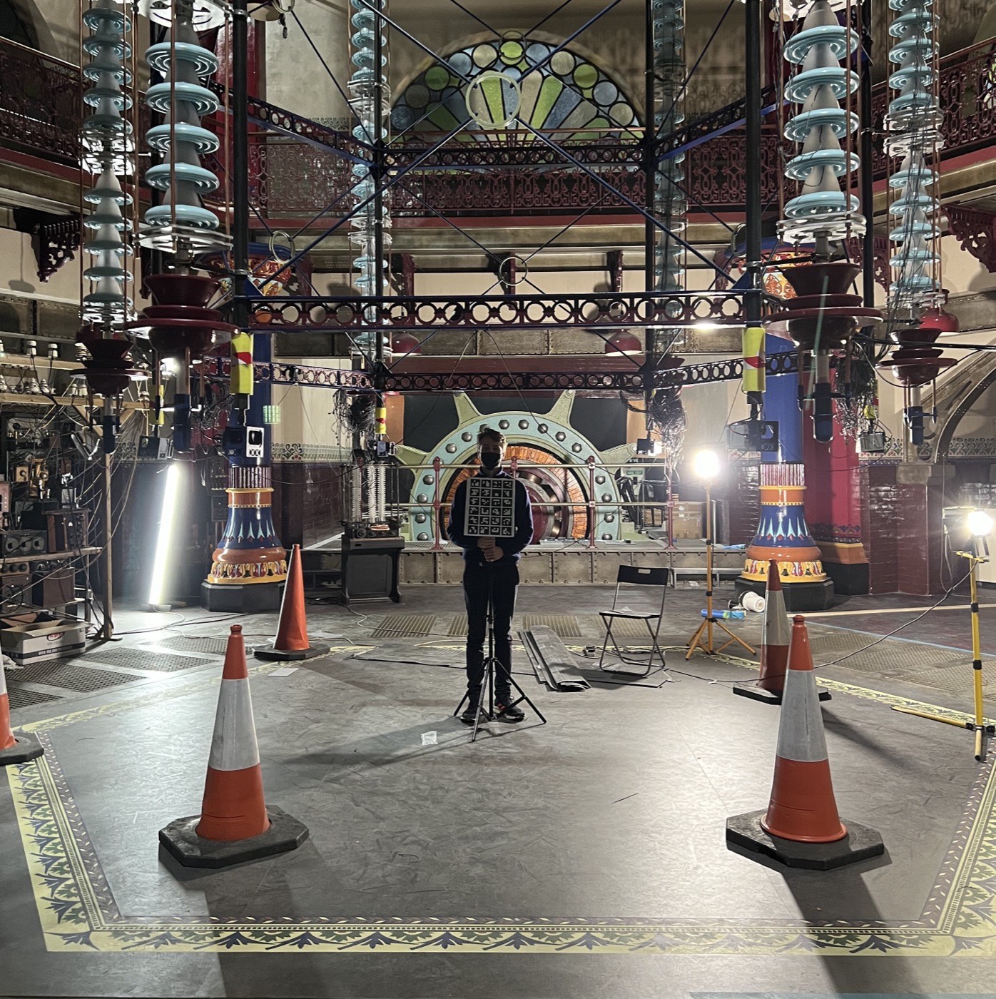 The shooting set — a Victorian ironwork interior with stained glass, traffic cones marking the capture volume, and a figure holding the calibration cube at its centre