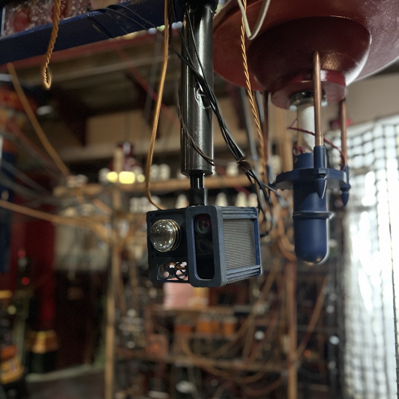 An Azure Kinect rigged overhead, sitting among the set's brass and ironwork