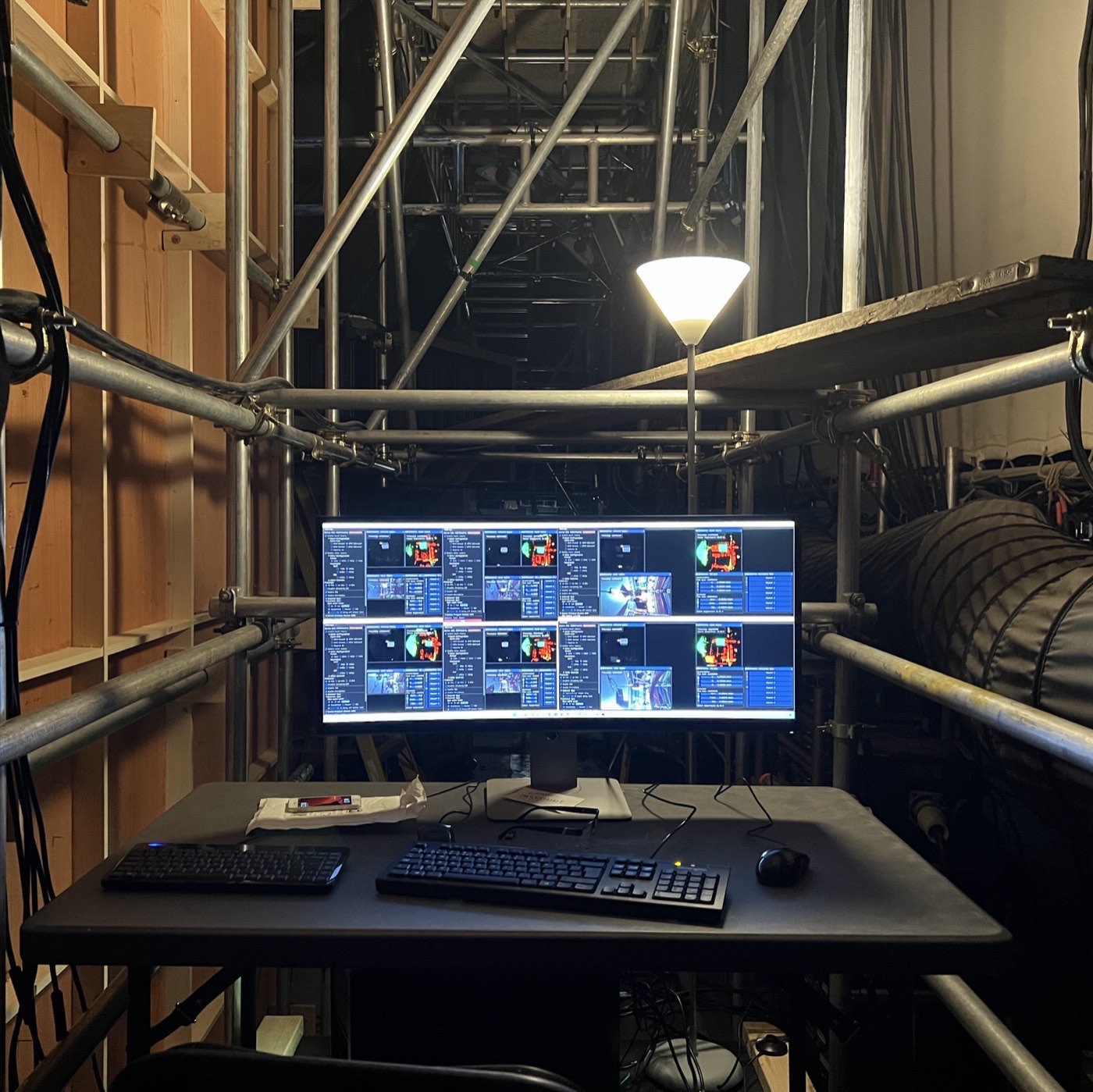 An operating desk built into scaffolding behind the set, an ultrawide monitor showing six depth camera feeds in a grid